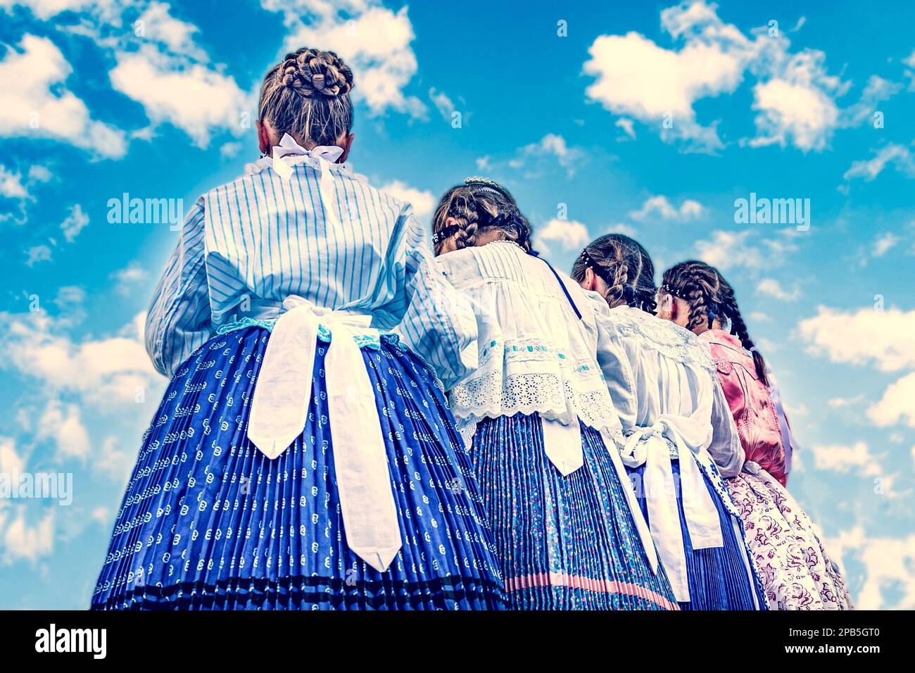 Danse folklorique des filles en costumes folkloriques sous le ciel bleu Banque D'Images