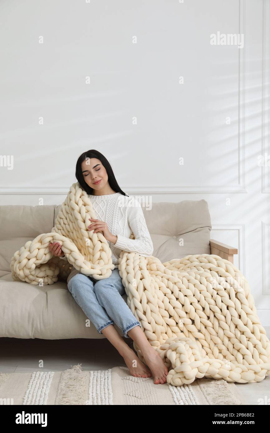 Jeune femme avec une couverture en grosse maille sur le canapé à la maison  Photo Stock - Alamy