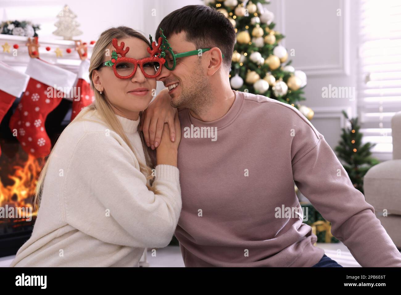 Couple charmant portant des verres de fête dans la chambre décorée pour Noël Banque D'Images