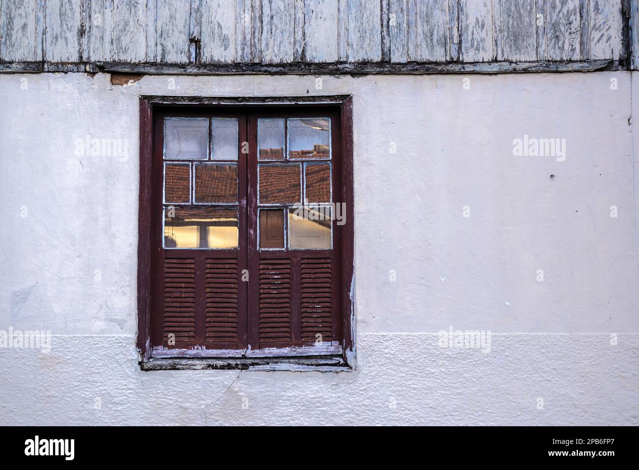 Fenêtre en bois marron dans une maison avec mur blanc. Dans les fenêtres vous pouvez voir le reflet des carreaux du bâtiment en face, dans une ville en BR Banque D'Images