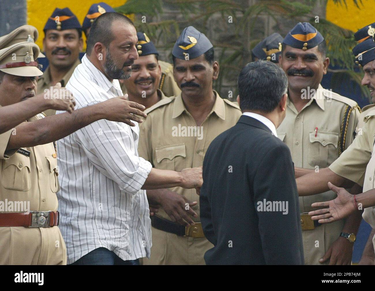 Bollywood star Sanjay Dutt, in white shirt, shakes hands with policemen ...