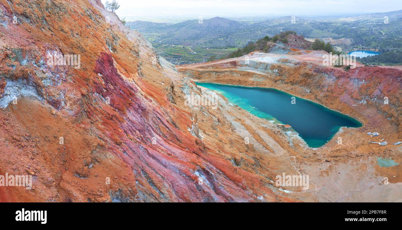 Les mines de cuivre abandonnées de Chypre. Goussan coloré (calotte de fer) de la mine Alesto à fosse ouverte remplie d'eau, et lac de la mine Memi à la distance Banque D'Images