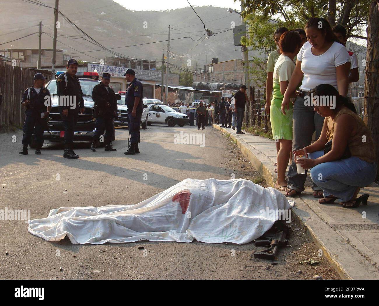 ** FILE ** Artemio Mejia, the police chief of Chilpancingo, lies dead on the ground near his home as his wife stands next to his body in the city of Chilpancingo, Mexico, in this May 9, 2007 file photo. Assailants cut off the vehicle of Mejia, and riddled him with bullets said local police authorities. In all, about 100 Mexican officers have been slain since President Felipe Calderon launched an ambitious nationwide crackdown on the drug trade this year. (AP Photo/Oscar Alvarado) Banque D'Images