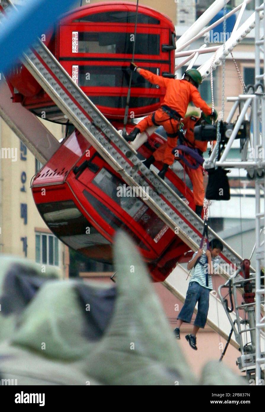 South Korean firefighters rescue a student from a car of a Ferris wheel at the World Carnival Busan, south of Seoul, Monday, Aug. 13, 2007. Two cars plummeted from a Ferris wheel and crashed into other parts of the ride in an amusement park in the southern city of Busan, killing as many as five people, news reports said Monday.(AP Photo/Yonhap, Jo Jung-ho) ** KOREA OUT ** Banque D'Images