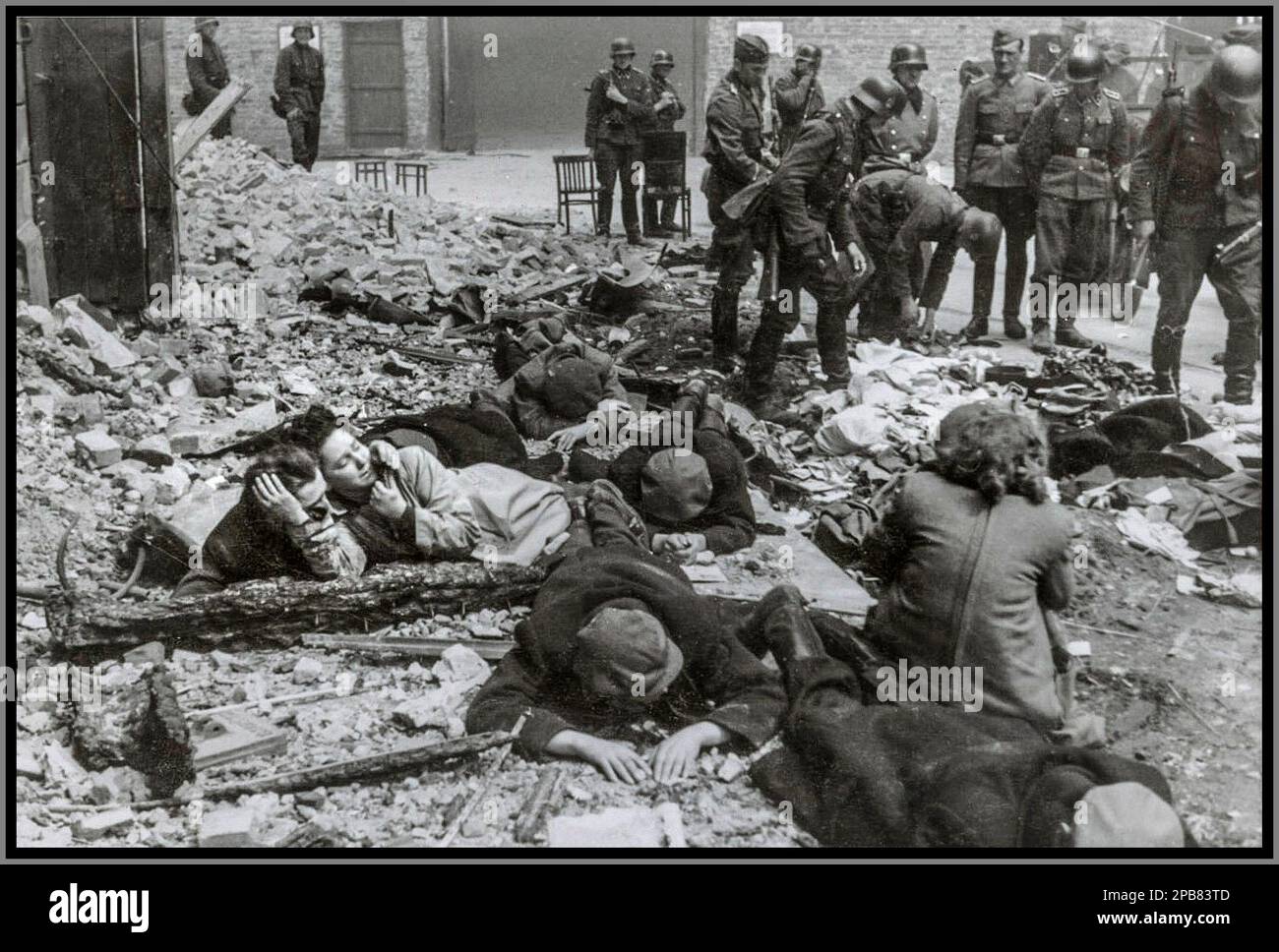 VARSOVIE occupation nazie les résidents juifs de Varsovie de la seconde Guerre mondiale se sont retirés d'un bunker, avec les SS Troopers de l'Allemagne nazie en action. Photo prise à Nowolipie Street regardant vers l'est, près de l'intersection avec Smocza Street, peut-être Nowolipie 64 / Smocza 1. À l'arrière, on peut voir le mur du ghetto avec une porte. Stroop Report Evidence United States Counsel for the Prosecution of Axis criminality ; United States pièces, 1933-46 Banque D'Images