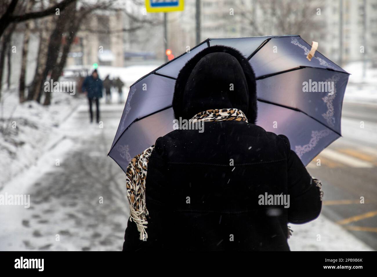 Moscou, Russie. 12th mars 2023. Une femme prend refuge sous un parapluie lors d'une chute de neige à Moscou, en Russie. Des conditions de neige, de pluie et de verglas sont attendues à Moscou le mois de mars. Banque D'Images