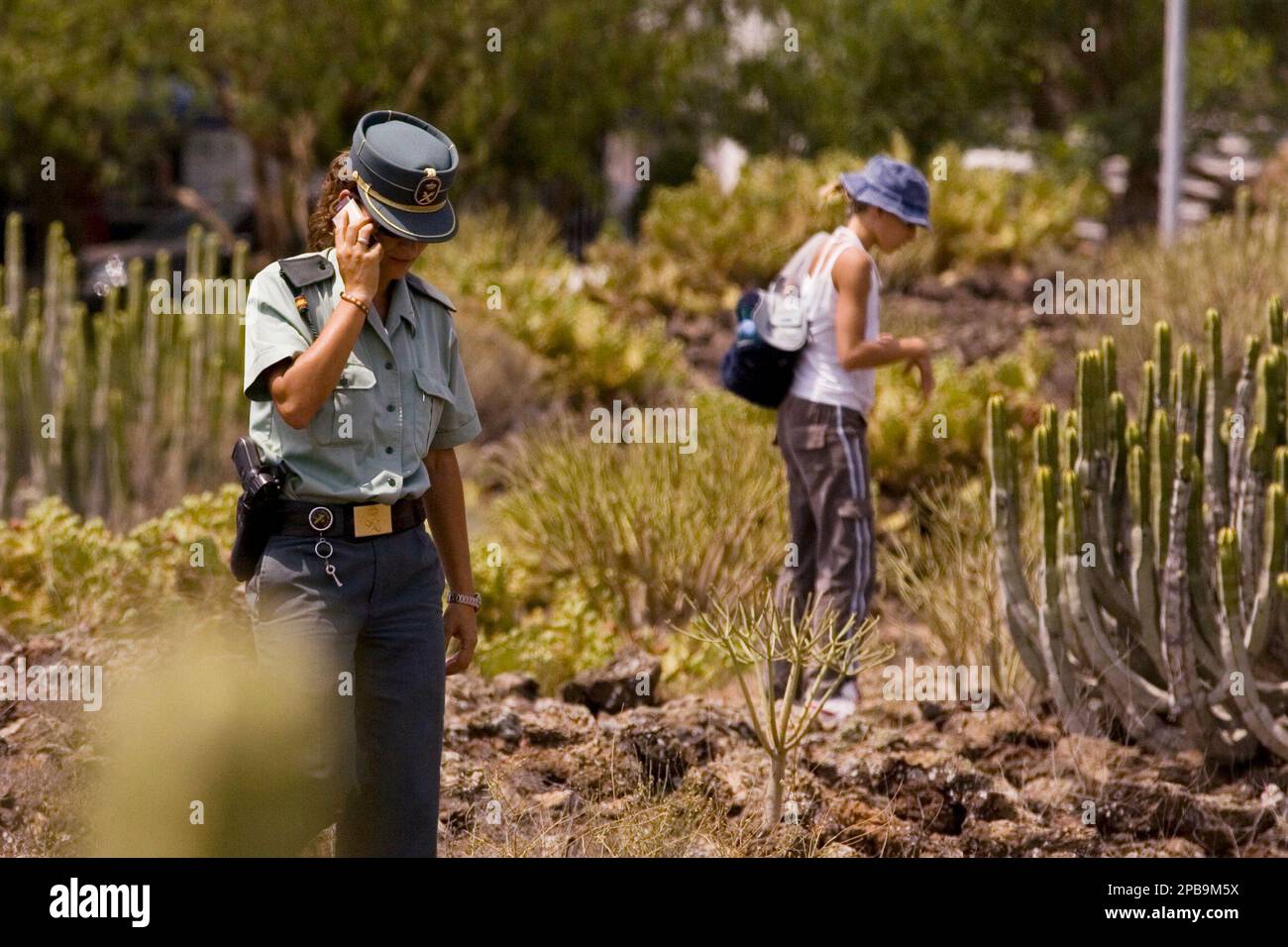 A Spainish civil guard officer and a volunteer look over rough ground, as they search for the missing Chilean girl Fernanda Fabiola Urzua, in Granadilla de Abona on the Canary Island of Tenerife, Spain, Saturday, July 28, 2007. Fifteen-years old Fernanda Fabiola was seen last, on the night of Thursday 26. Police officers, soldiers and volunteers joined in the search. This is the second mysterious disappearance in Tenerife this year. (AP Photo/Arturo Rodriguez) Banque D'Images