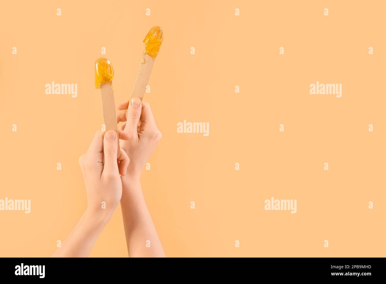 Mains de femmes tenant des spatules avec pâte de sugarde sur fond beige Banque D'Images
