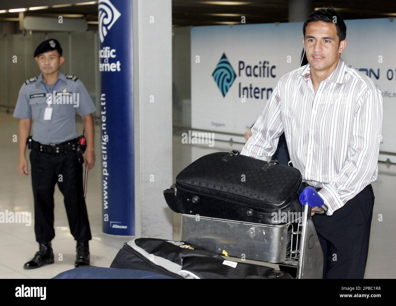 Australia's soccer player Tim Cahill pushes his cart past a security guard as he arrives at Suvarnabhumi international airport in Bangkok, Thailand Wednesday, July 4, 2007. Australia will play in AFC Asian Cup 2007 group-A matches in Bangkok against Iraq, Oman and Thailand on July 8, 13 and 16, 2007. (AP Photo/Apichart Weerawong) Banque D'Images