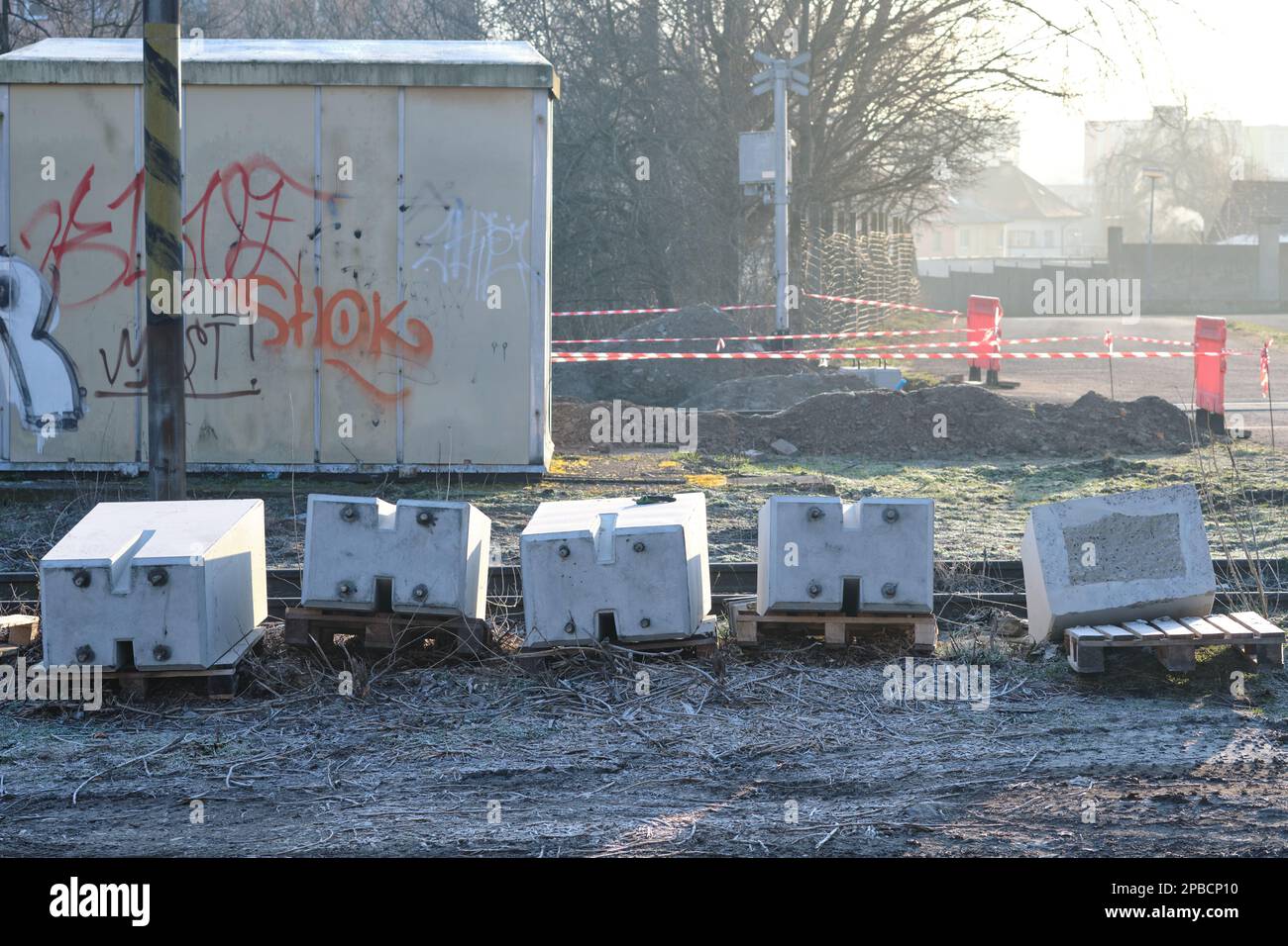 Blocs de béton sur des palettes préparés pour la construction d'un passage à niveau placé sur le sol avec l'infrastructure ferroviaire en arrière-plan Banque D'Images