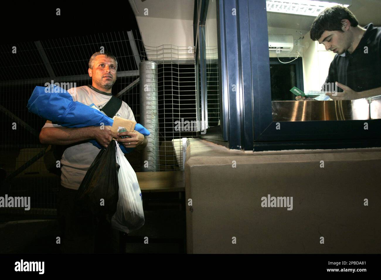 Palestinian Gaza resident Naim Elyam, left, carrying his three-month-old dead son, who died on natural causes as he was receiving treatment in an Israeli hospital, waits as he has his documents checked by an Israeli security official, right, at the Erez border crossing, Monday June 18, 2007 in order to enter the Gaza Strip. Israeli soldiers and Palestinian gunmen exchanged fire Monday at the Erez crossing between Israel and Gaza, killing one Palestinian and wounding at least 10, the Israeli rescue service and Palestinian hospital officials said. The Israeli military said Palestinians threw a g Banque D'Images