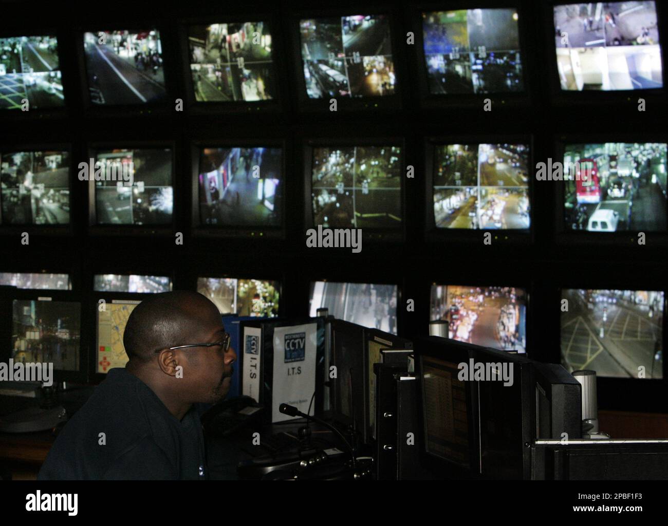 A worker watches and examines a wall of video monitors showing