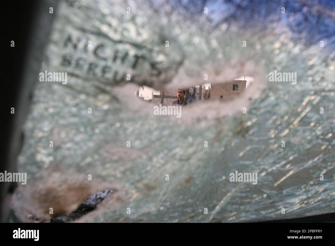 An Iraqi man is seen through a hole of the shattered window of a car after an attack by U.S. warplanes and helicopter in Sadr City district of Baghdad on Saturday, May 26, 2007. The U.S. airstrike hit a gas station, causing widespread damage to 10 vehicles, killing three people and wounding eight civilians the police said. (AP Photo/Karim Kadim) Banque D'Images