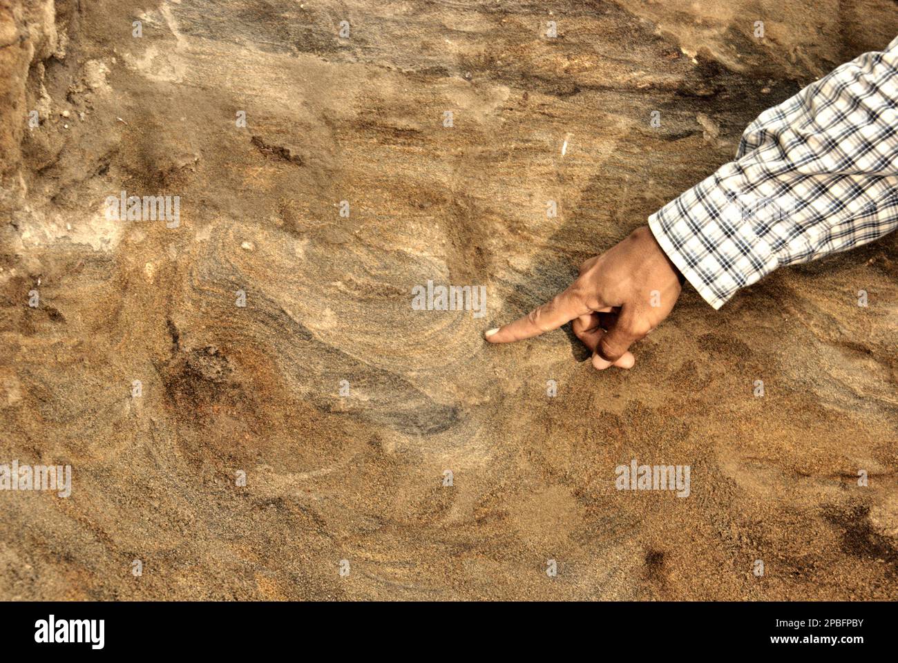Le paléontologue Iwan Kurniawan souligne une marque sur les couches de sol en expliquant un processus géologique lors de l'excavation des os fossilisés d'Elephas hysudrindicus, une espèce d'éléphant éteinte vécue pendant l'époque du Pléistocène, plus tard connue sous le nom d'éléphant de Blora Comme son équipe travaille en arrière-plan sur le site d'excavation de Sunggun, Mendalem, Kradenan, Blora, Central Java, Indonésie. L'équipe de recherche sur les vertébrés (Agence géologique, Ministère indonésien de l'énergie et des ressources minérales) dirigée par Kurniawan lui-même avec Fachroel Aziz a découvert les os de l'espèce presque... Banque D'Images