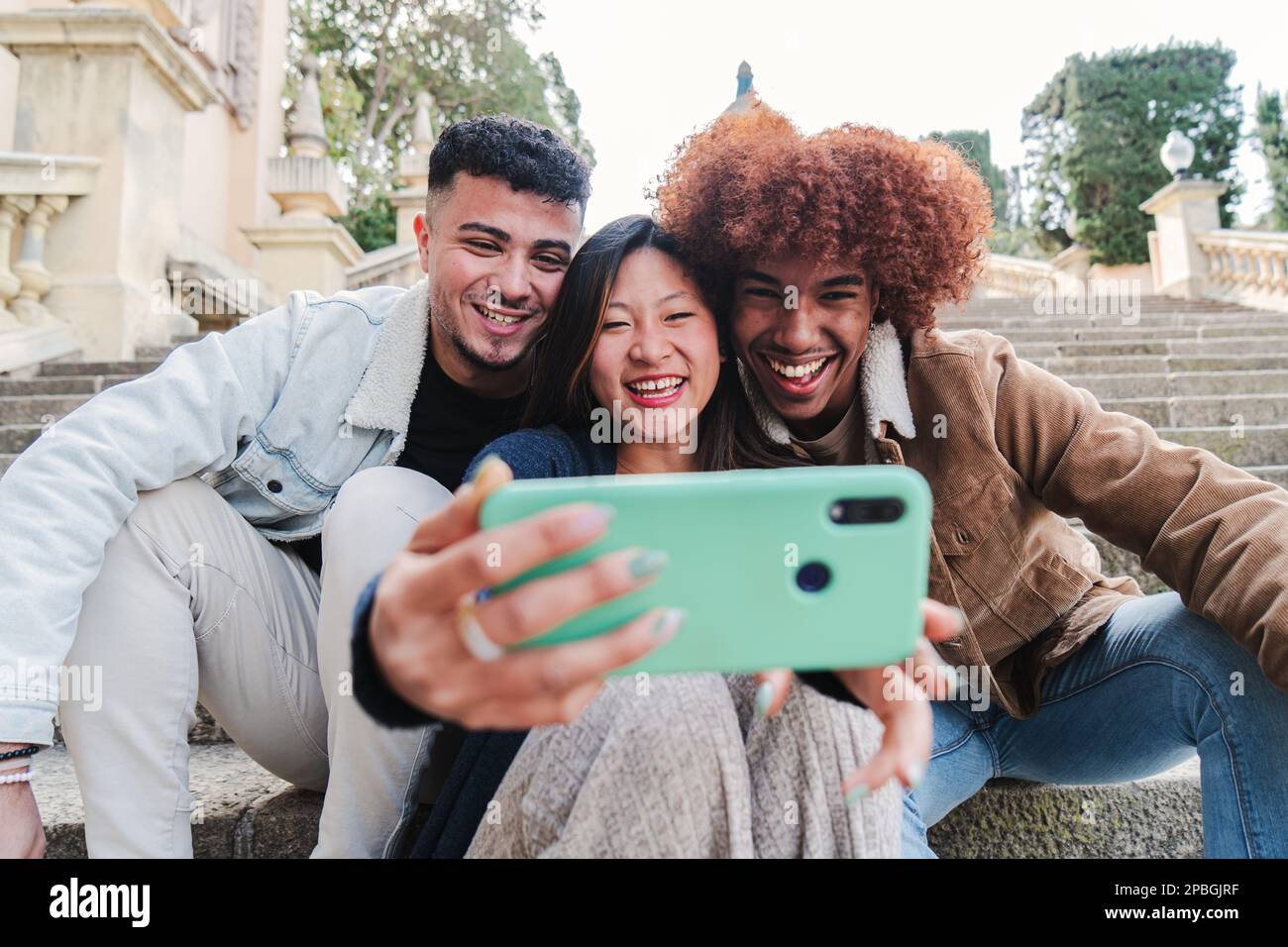Groupe d'amis multiraciaux adolescents qui s'amusent à prendre un portrait de selfie avec un téléphone portable. Trois jeunes gens heureux souriant et regardant des vidéos drôles ou ayant un appel vidéo avec un téléphone cellulaire . Photo de haute qualité Banque D'Images