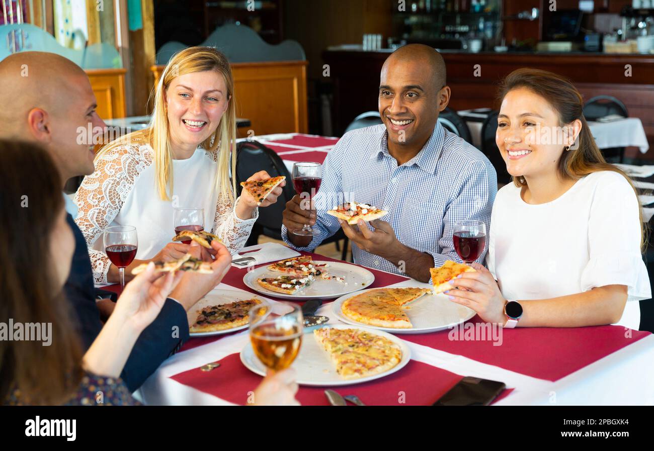 Les jeunes adultes sont gais et apprécient la pizza dans un restaurant confortable Banque D'Images