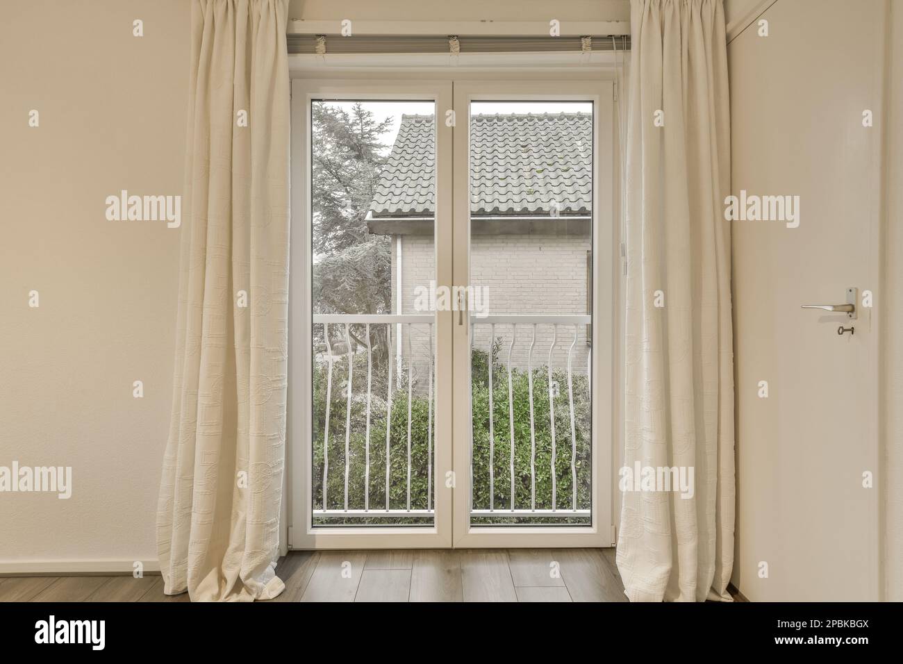 une fenêtre ouverte avec des rideaux à l'extérieur, et un chat assis au milieu donnant sur la vue Banque D'Images