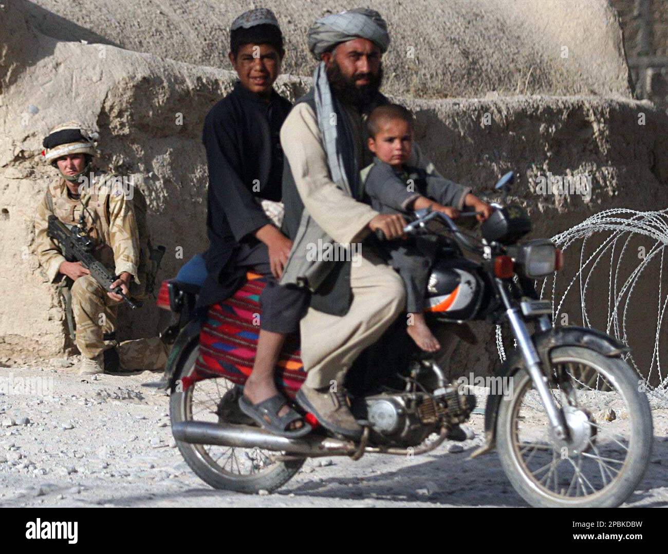 A British soldier of the 2nd Royal Regiment of Fusiliers looks on as an Afghan man rides a bike in Sangin, in northern Helmand province, Afghanistan, Monday, April 23, 2007. Afghan forces have trapped up to 200 Taliban in a southern village, possibly including the militia's military commander Mullah Dadullah, Afghan officials claimed on Monday. (AP Photo/Rafiq Maqbool) Banque D'Images
