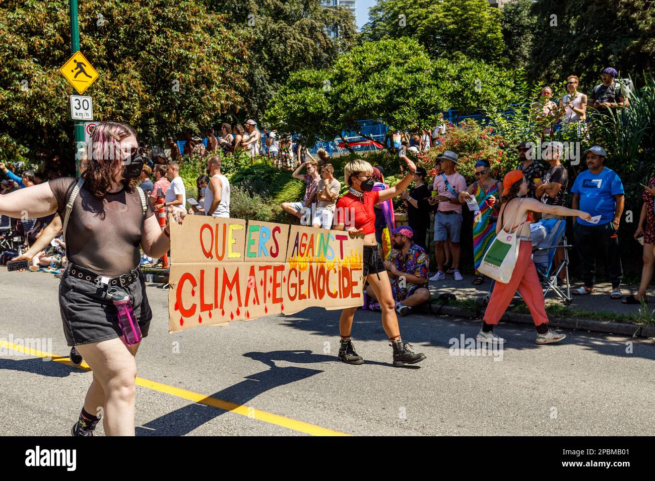 Vancouver, Canada - 31 juillet,2022: Les gens marchent sur la rue Pacific avec un énorme panneau Queuers contre le génocide climatique pendant la parade de la fierté Banque D'Images