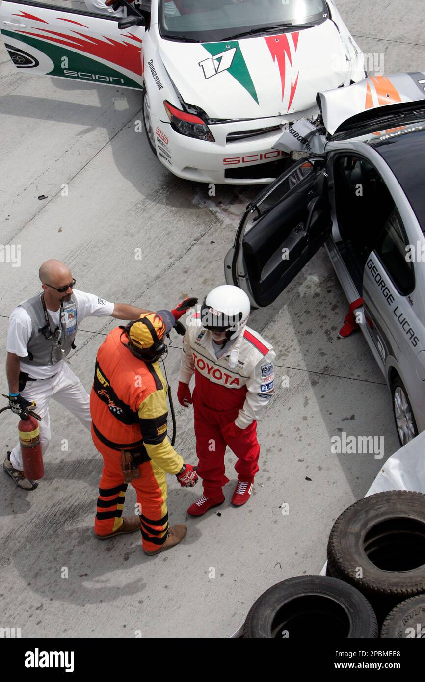 Race safety crew check on movie magnate George Lucas as he walks away from the No. 2 Toyota Scion tCs after he and and charity auction winner Annamarie Dean in the No. 17 car collided on Turn 1 in the Toyota Pro/Celebrity Race on the street course of the Toyota Grand Prix of Long Beach in Long Beach, Calif., Saturday, April 14, 2007. Lucas said "I thought I'd better do it (pass) ... I got a little too ambitious." (AP Photo/Reed Saxon) Banque D'Images