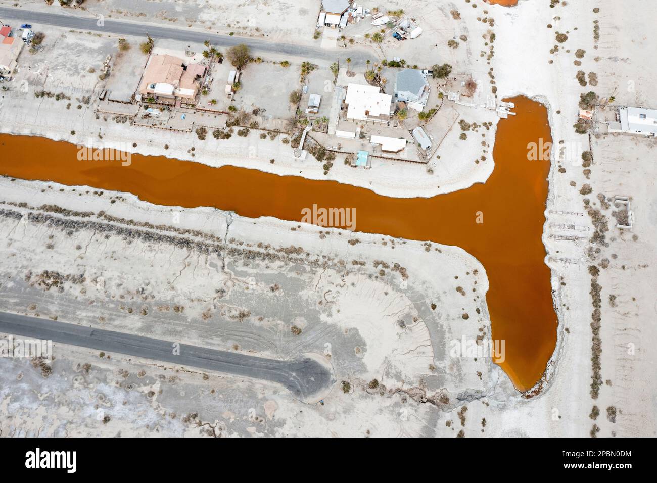 La mer de Salton est l'un des problèmes environnementaux les plus épineux de l'Occident américain. Le lac se rétrécit en raison de la sécheresse persistante, des transferts d'eau vers les villes voisines et de la diminution des entrées de ruissellement agricole alimentées par le fleuve Colorado. À Desert Shores, une communauté située sur le bord ouest de la mer de Salton, le rivage en recul a coupé le port de plaisance de la ville du reste du lac. Les polluants et les microbes salants ont transformé l'eau stagnante et nauséabonde en une teinte rougeâtre éclatante. Banque D'Images