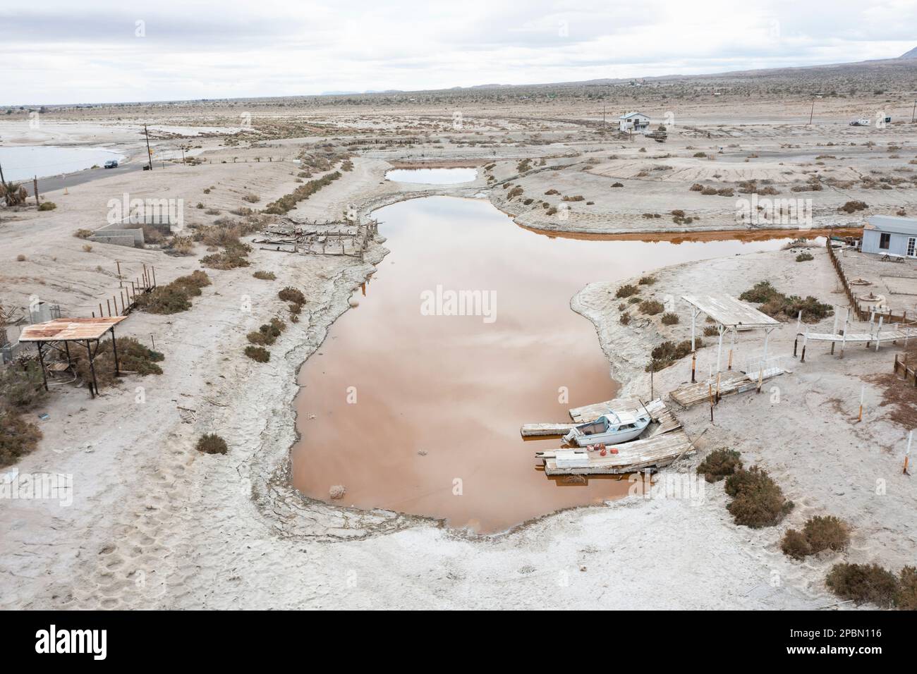 La mer de Salton est l'un des problèmes environnementaux les plus épineux de l'Occident américain. Le lac se rétrécit en raison de la sécheresse persistante, des transferts d'eau vers les villes voisines et de la diminution des entrées de ruissellement agricole alimentées par le fleuve Colorado. À Desert Shores, une communauté située sur le bord ouest de la mer de Salton, le rivage en recul a coupé le port de plaisance de la ville du reste du lac. Les polluants et les microbes salants ont transformé l'eau stagnante et nauséabonde en une teinte rougeâtre éclatante. Banque D'Images