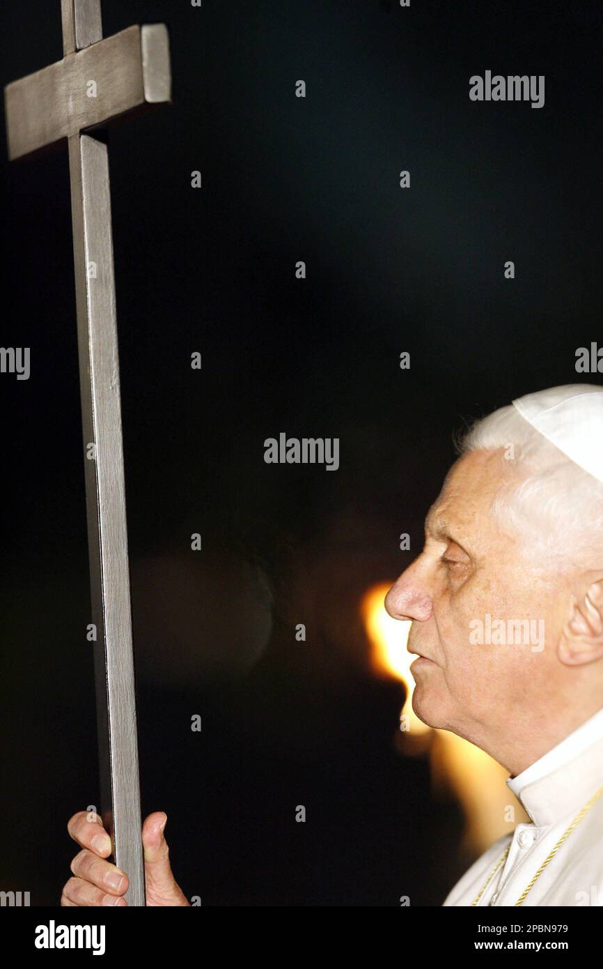 Pope Benedict XVI holds the wooden cross next to a torch, during the