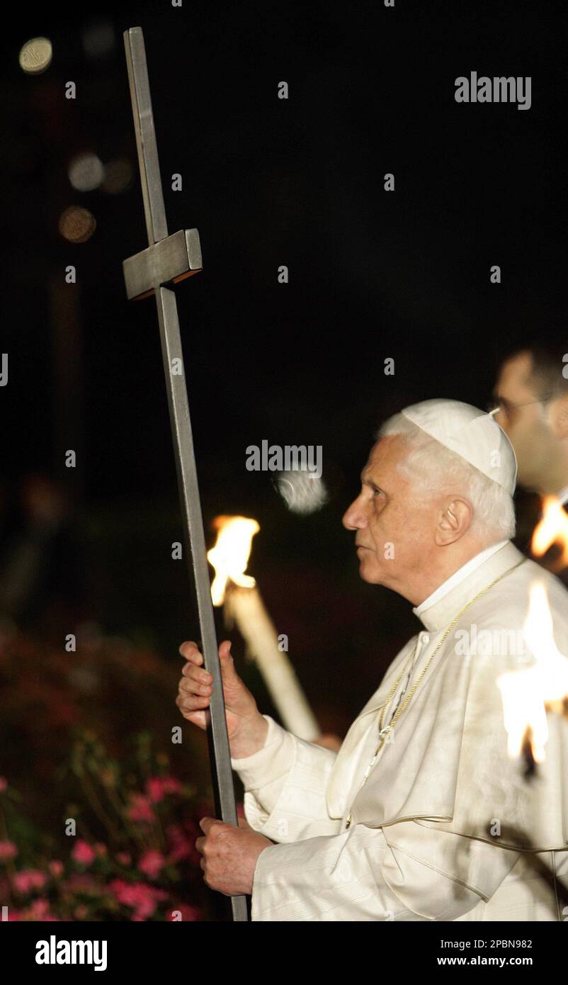 Pope Benedict XVI holds the wooden cross next to a torch, during the