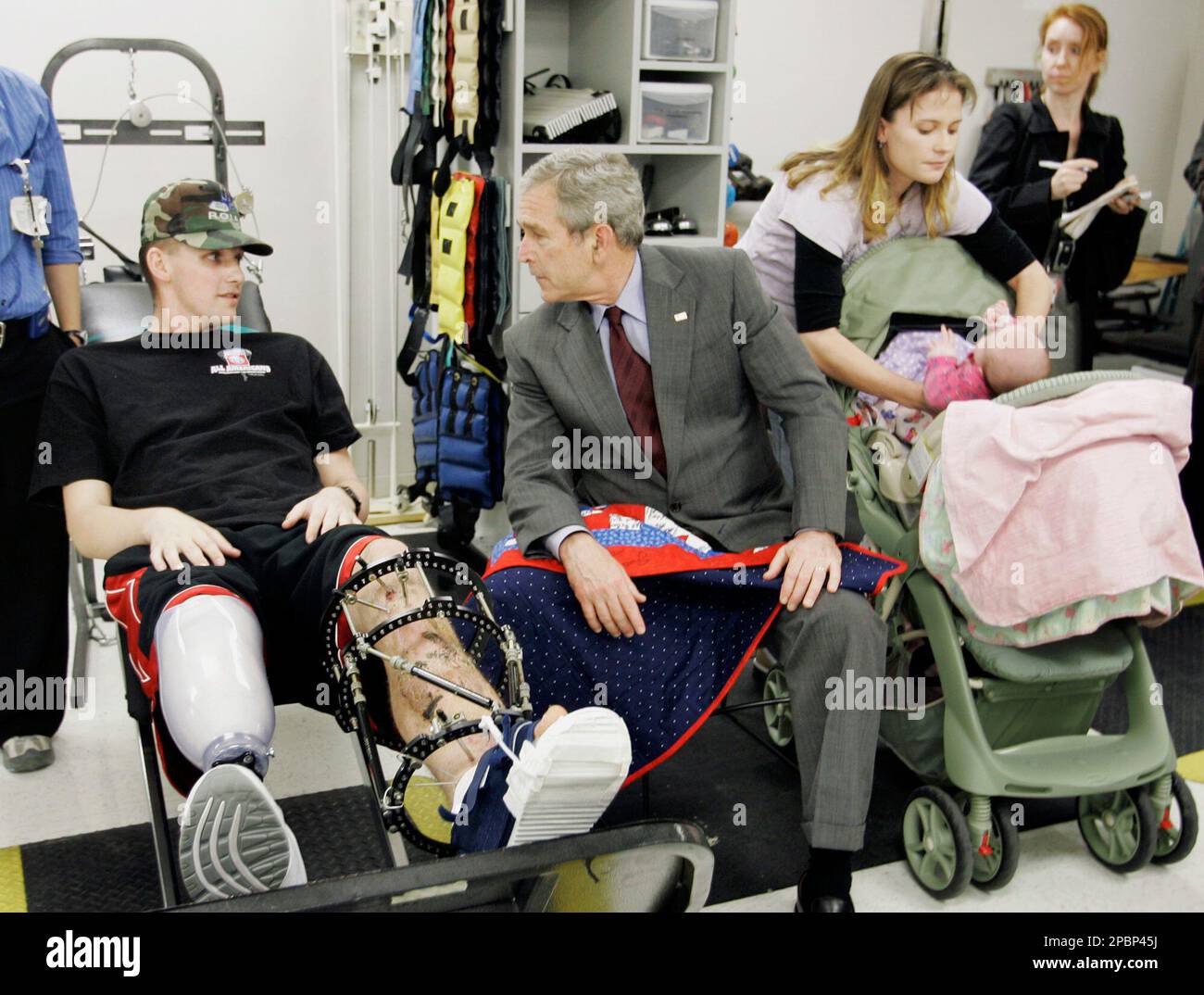 President Bush, center, talks with Sgt. David Gardner, left, from Ft. Bragg, N.C., who was wounded in Iraq, left, during a visit with patients at the physical therapy wing of Walter Reed Army Center in Washington, Friday, March 30, 2007. At right is Gardner's wife Beverly Gardner with child Hailey Gardner. (AP Photo/Gerald Herbert) Banque D'Images