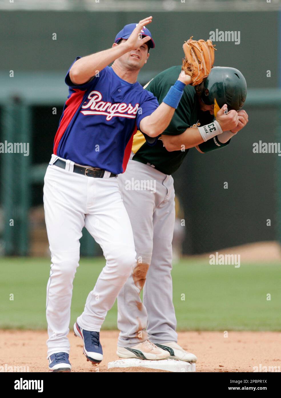 Oakland Athletics' Nick Swisher, right, covers up as Texas Rangers shortstop Michael Young nearly bumps into him while making a catch on a popup by Mike Piazza in the first inning of a spring training baseball game in Surprise, Ariz., Saturday, March 24, 2007. (AP Photo/Tony Gutierrez) Banque D'Images