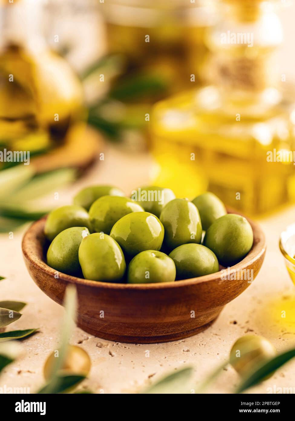 Olives vertes dans un bol avec feuilles sur la table, gros plan Banque D'Images