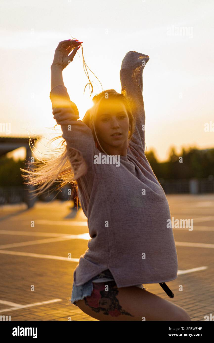 La femme danse au coucher du soleil, en mouvement, cheveux volants. Banque D'Images