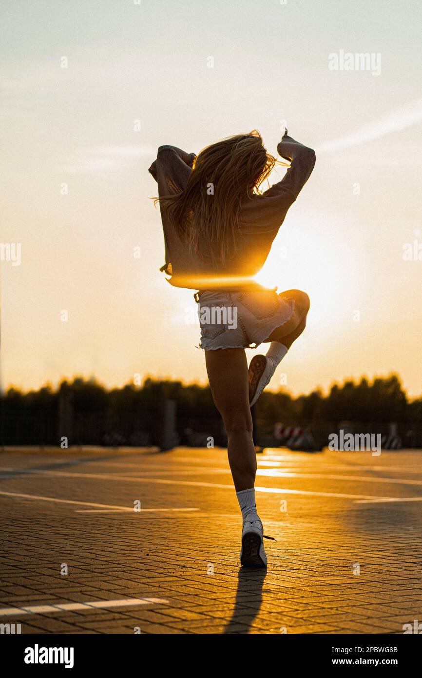 La femme danse au coucher du soleil, en mouvement, cheveux volants. Banque D'Images