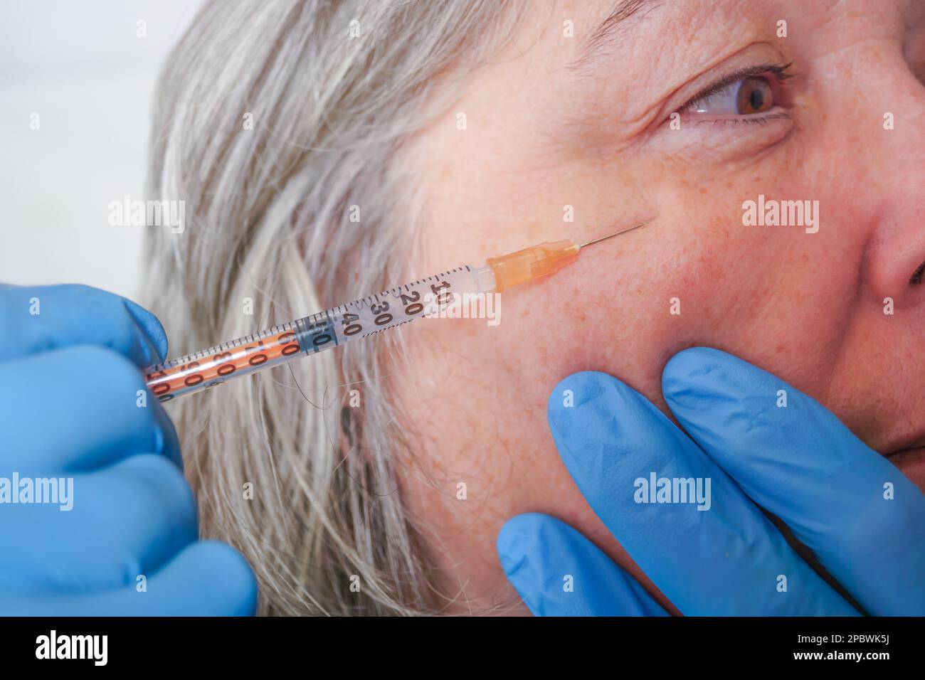 Gros plan des mains du cosmétologue injectant du botox dans le visage de la femme. Banque D'Images