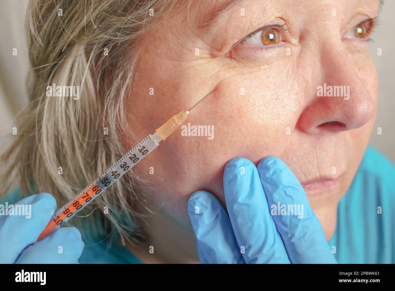 Gros plan des mains du cosmétologue injectant du botox dans le visage de la femme. Banque D'Images