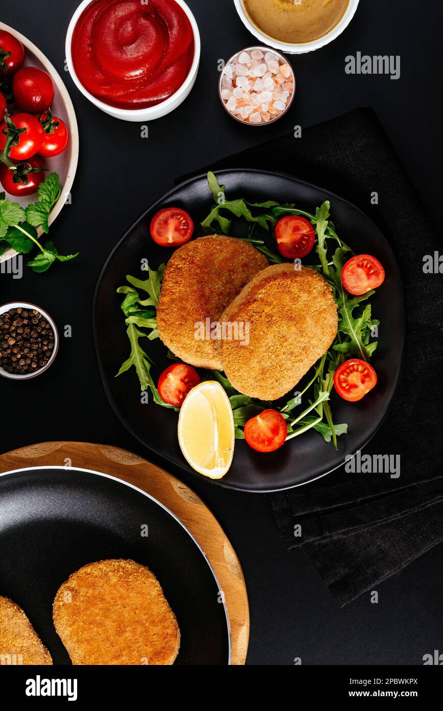escalope de poulet sur une assiette noire. légumes et herbes. bac noir Banque D'Images