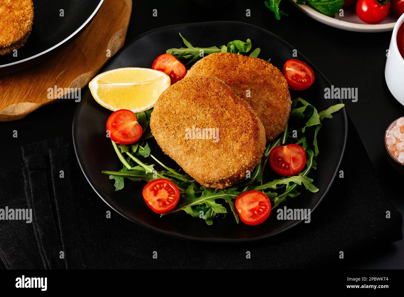 escalope de poulet sur une assiette noire. légumes et herbes. bac noir Banque D'Images