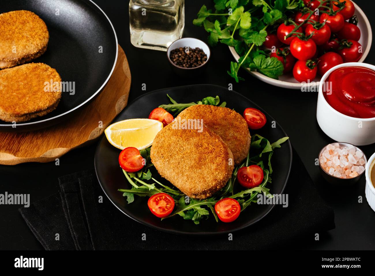 escalope de poulet sur une assiette noire. légumes et herbes. bac noir Banque D'Images