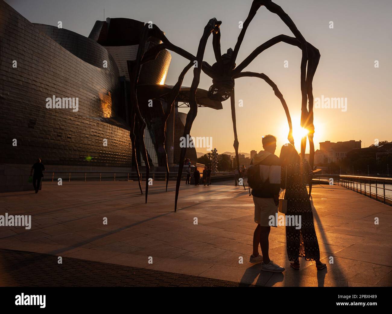 Bilbao, Espagne - 02 août 2022: Quelques touristes prennent un selfie au coucher du soleil à côté de l'araignée, la sculpture de Louise Bourgeois intitulée Mamam in Th Banque D'Images