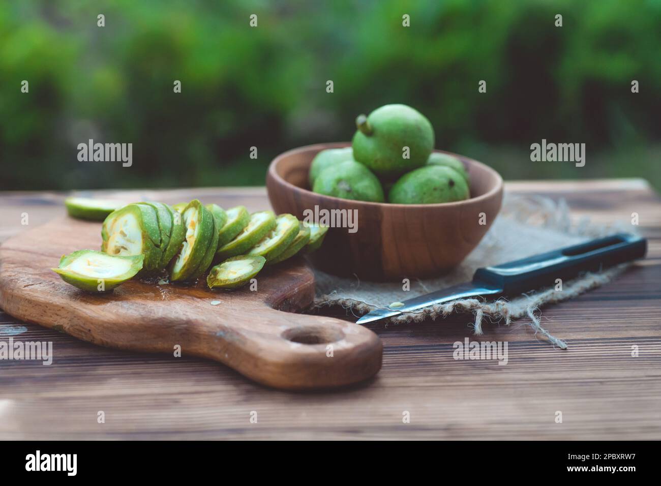 une alimentation saine.Les noix, coupées en tranches, sont dispersées sur une planche à découper.Ancienne table vintage et fruits de noyer entiers non mûrs. Banque D'Images