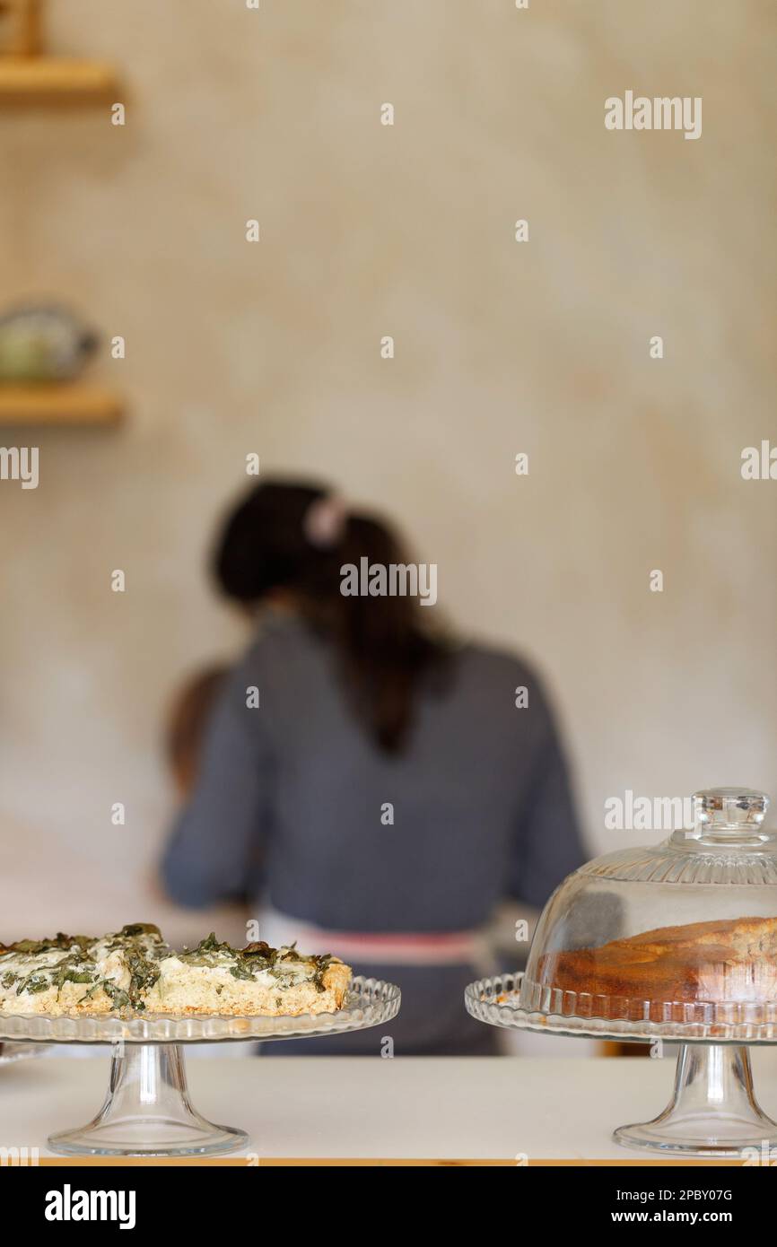 Portrait de serveuse en tablier depuis l'arrière, debout au comptoir du magasin et faisant du travail, gâteau maison et tarte sur un coin de café, concept d'affaires familiales. Banque D'Images