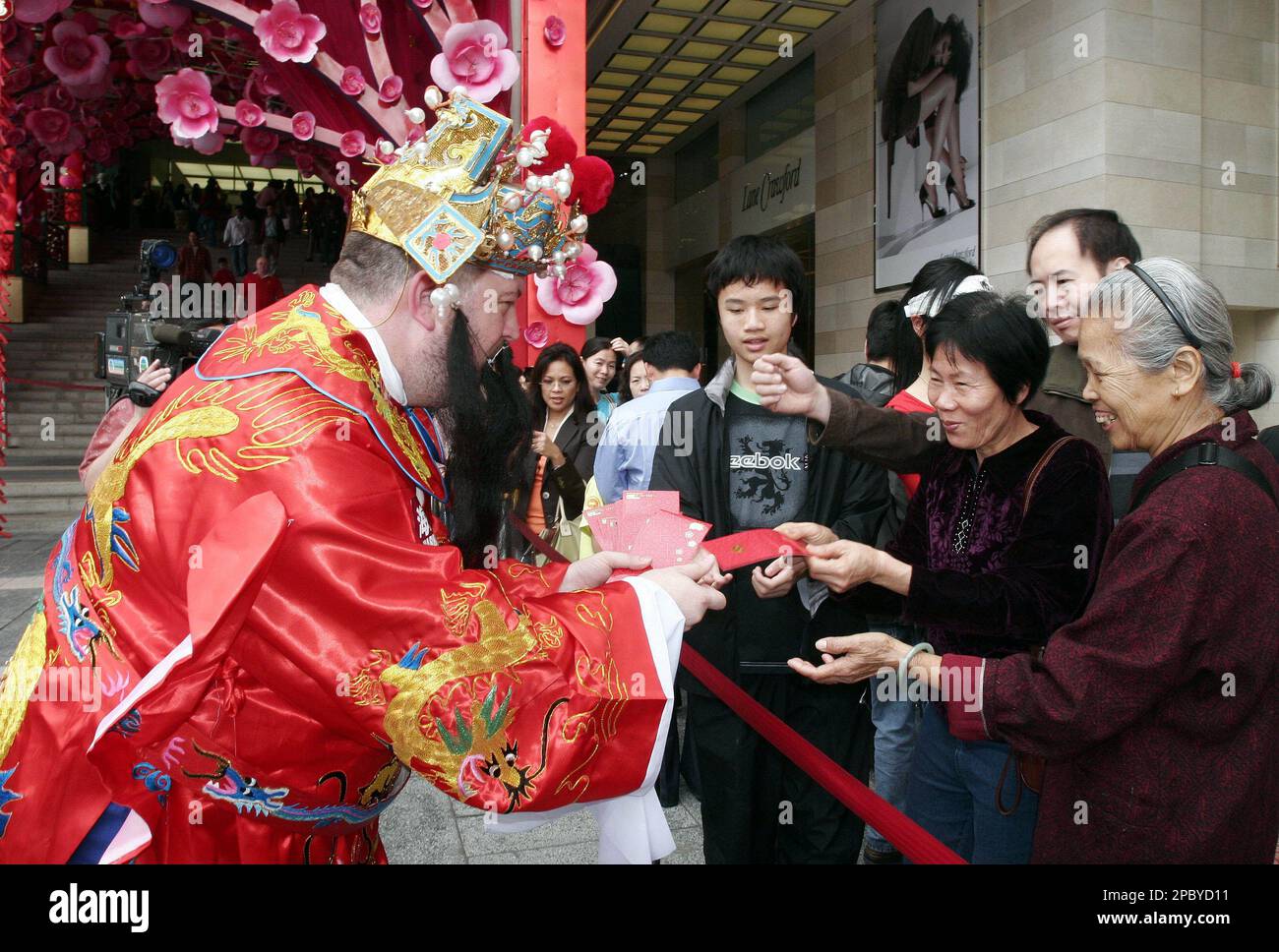 A man dressed as Chinese "God of Fortune" hands out red packets with "lucky money" in them outside a shopping mall to celebrate the first day of the Chinese new year in Hong Kong Sunday, Feb. 18, 2007. Handing out lucky money is traditional practice based on helping out poor people to equally celebrate the New Year. (AP Photo/Vincent Yu) Banque D'Images