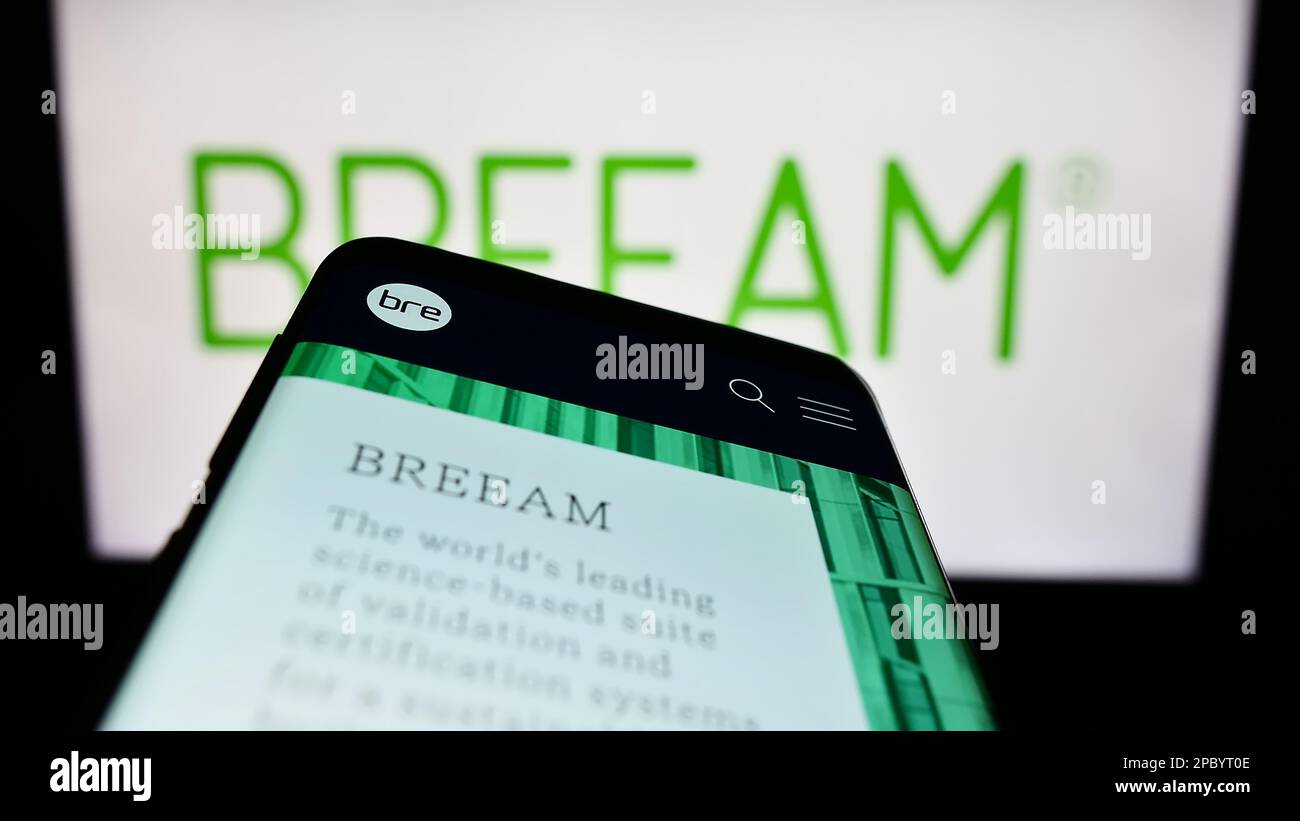Smartphone avec site Web de certification de bâtiment vert BREEAM à l'écran devant le logo. Faites la mise au point dans le coin supérieur gauche de l'écran du téléphone. Banque D'Images