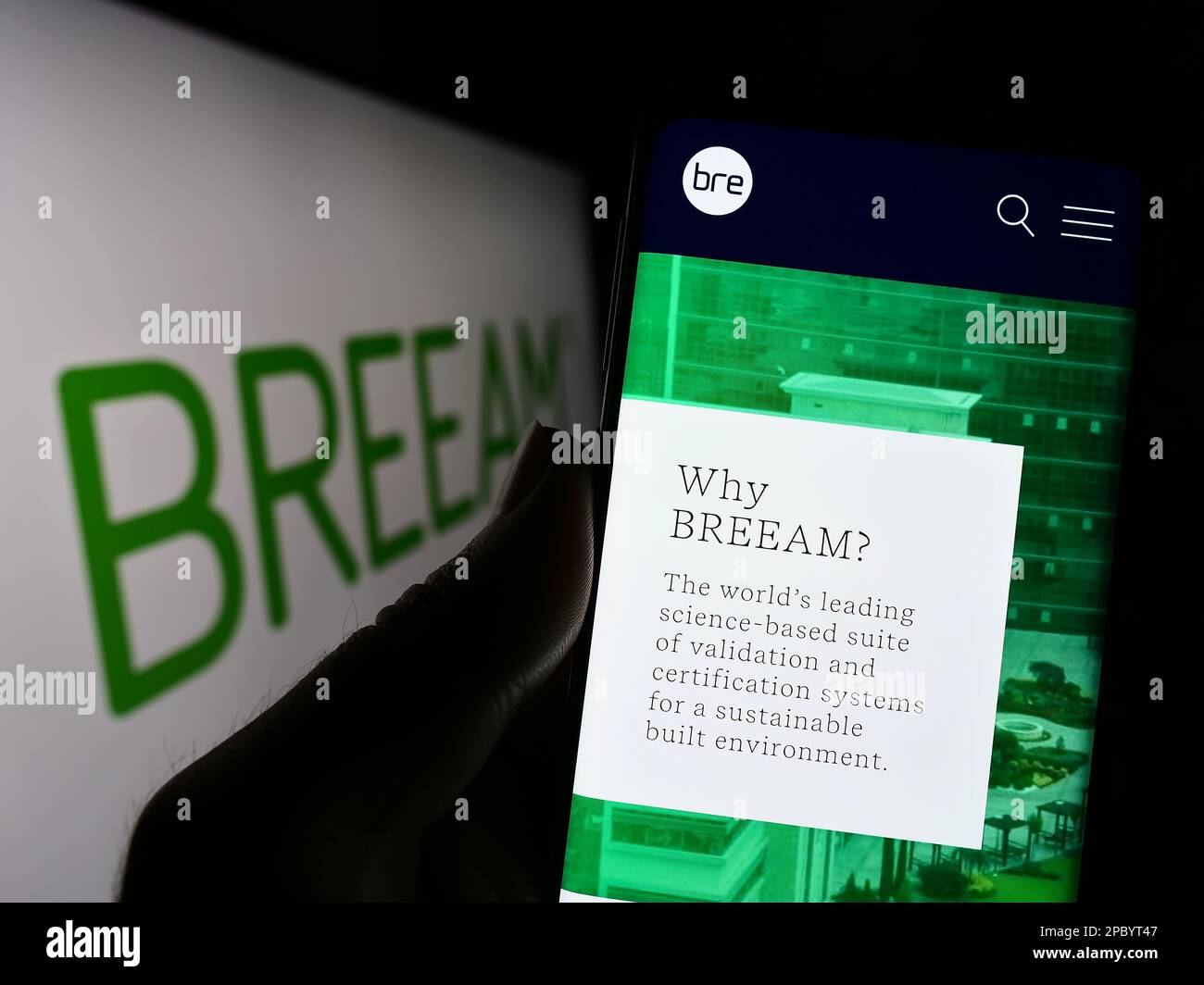 Personne tenant un téléphone portable avec une page web de certification de bâtiment vert BREEAM à l'écran devant le logo. Concentrez-vous sur le centre de l'écran du téléphone. Banque D'Images