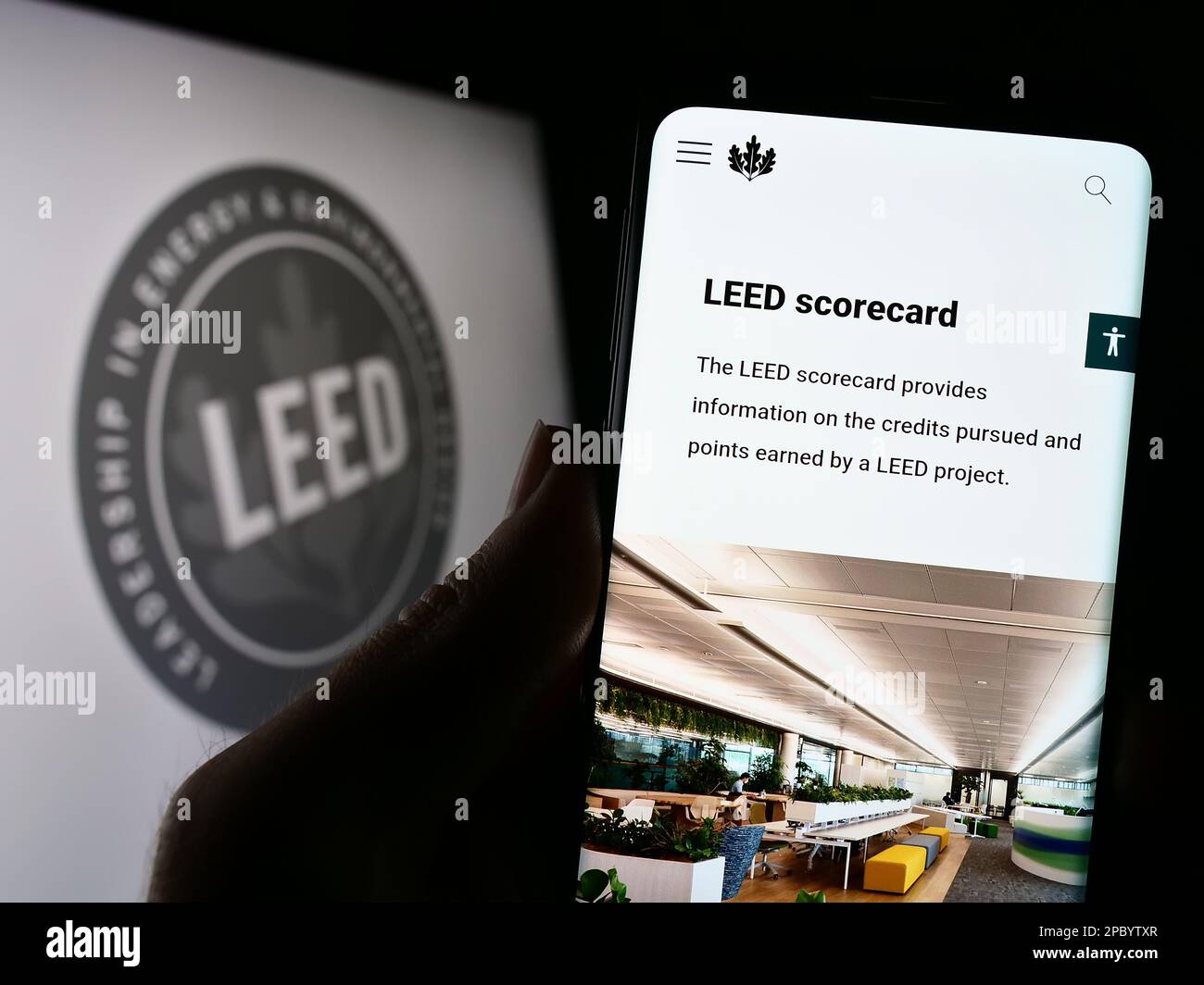 Personne tenant un téléphone portable avec une page Web de la certification américaine LEED pour bâtiments écologiques à l'écran devant le logo. Concentrez-vous sur le centre de l'écran du téléphone. Banque D'Images