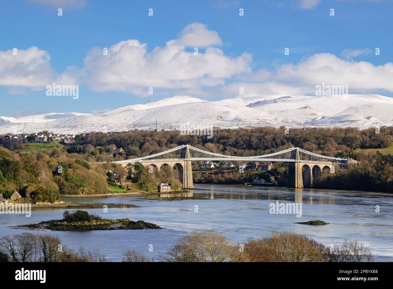 Vue panoramique sur le pont suspendu de Menai traversant le détroit de Menai avec de la neige sur les montagnes en hiver. Pont Menai (Porthaethwy), île d'Anglesey, pays de Galles, Royaume-Uni Banque D'Images