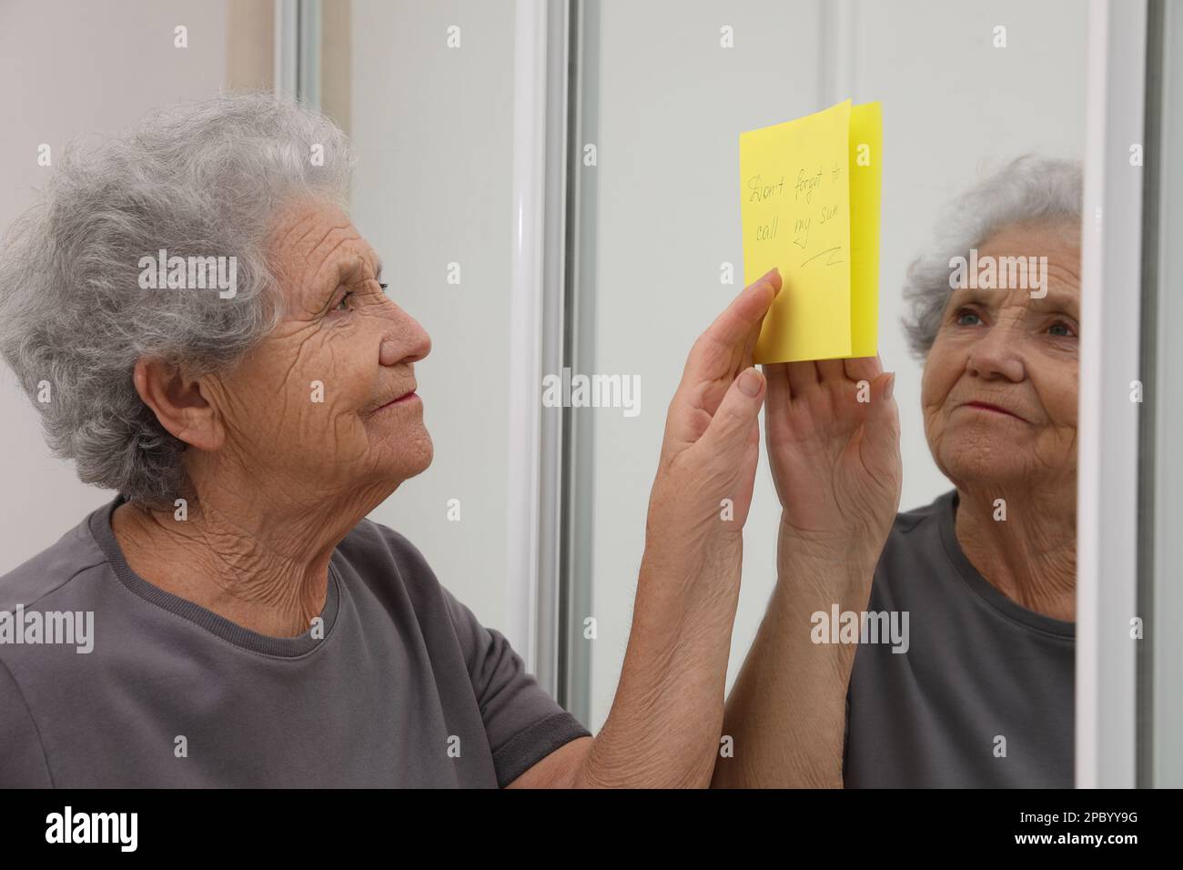 Femme âgée regardant la note de rappel à l'intérieur. Perte de mémoire liée à l'âge Banque D'Images