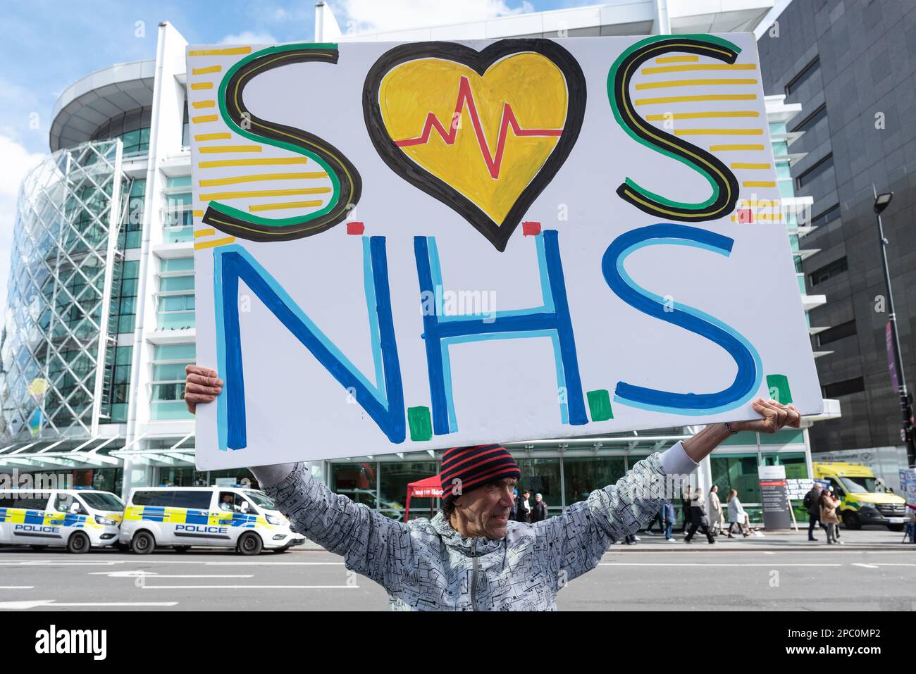 Londres, Royaume-Uni. 11 mars 2023. Un manifestant tient un écriteau disant « OS NHS », avec l'hôpital UCH en arrière-plan, comme personnel du National Health Service et su Banque D'Images Londres, Royaume-Uni. 11 mars 2023. Un manifestant tient un écriteau disant « OS NHS », avec l'hôpital UCH en arrière-plan, comme personnel du National Health Service et su Banque D'Images