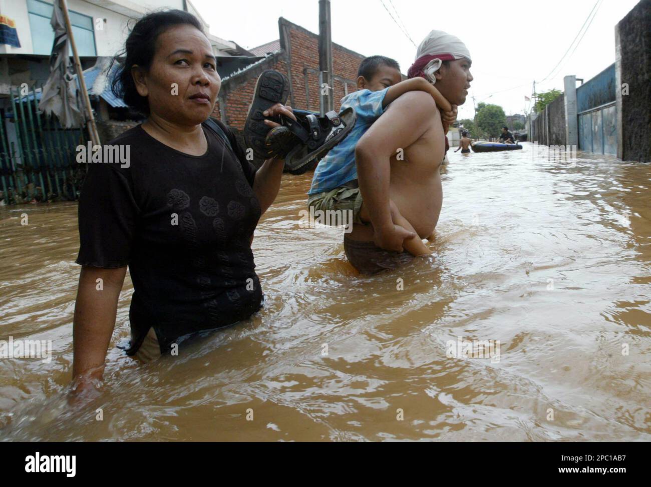 Residents wade through a flooded street in Jakarta, Indonesia, Monday, Feb. 5, 2007. Boats ferried emergency supplies to desperate residents of Indonesia's flood-stricken capital as overflowing rivers again burst their banks following days of rain. At least 25 people have been killed and almost 340,000 others made homeless, officials said. (AP Photo/Achmad Ibrahim) Banque D'Images
