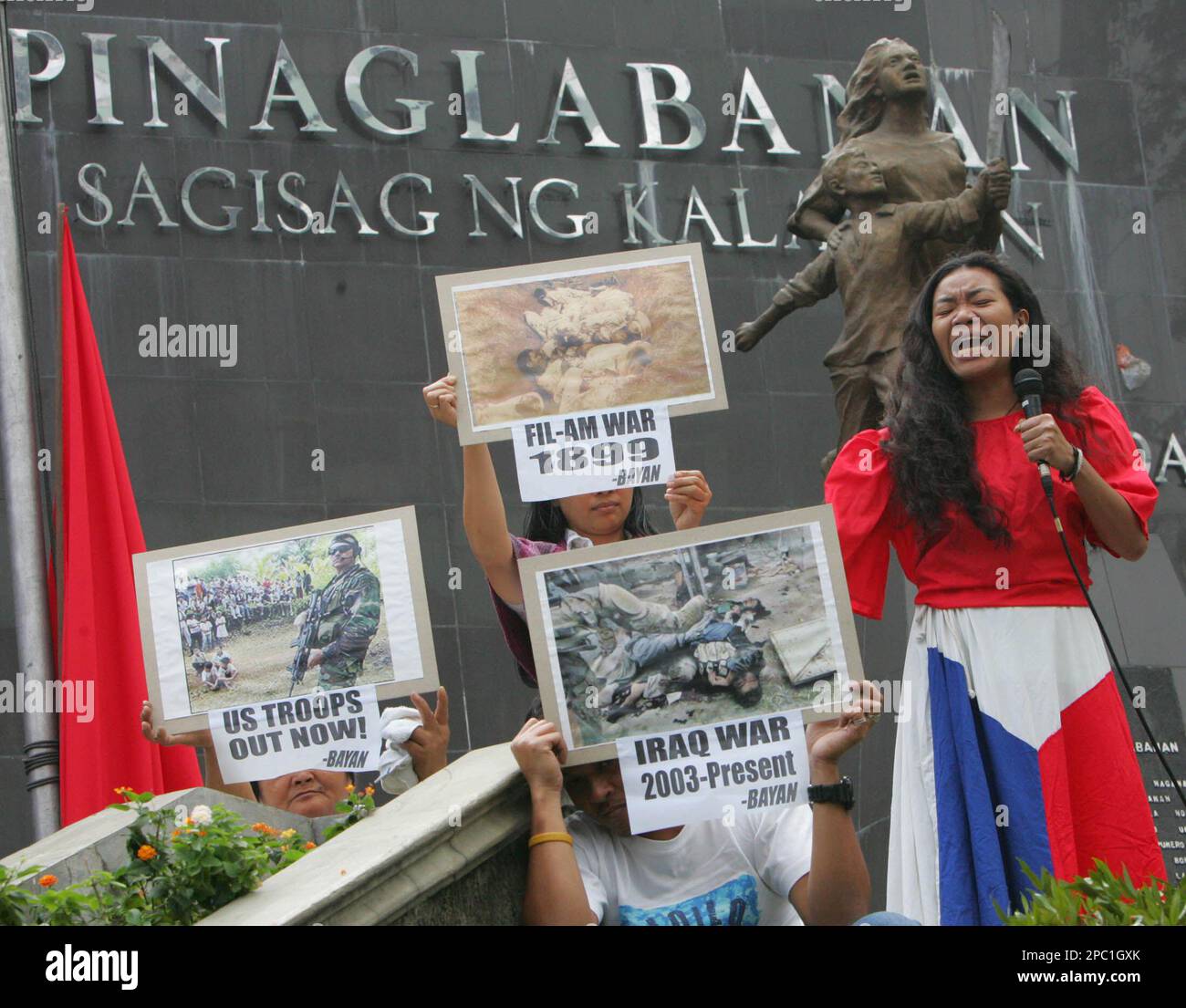 A woman in costume performs as others display anti U.S. posters during a play on the eve of the commemoration of the 108th anniversary of the Filipino-American War in 1899 Saturday, Feb. 3, 3007, in San Juan east of Manila, Philippines. The performers portrayed Filipinos who were still under fire from an alleged American interventionist policy and demanded a public apology from the U.S. government for the death of some 300,000 Filipinos killed during the war. (AP Photo/Pat Roque) Banque D'Images